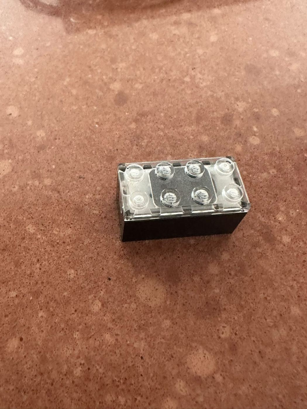 El SMART Brick de LEGO fuera del modelo, un 2x4 con los studs metalizados, foto propia de 2026